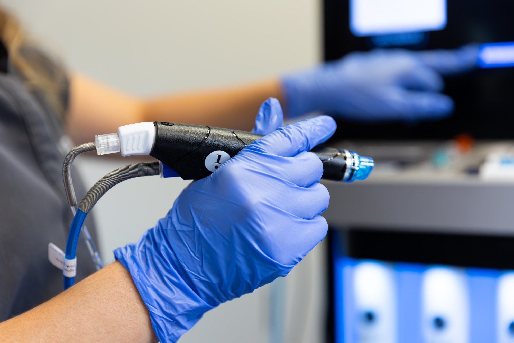 Gloved provider holding the Hydrafacial tool in preparation for a facial in Plano.