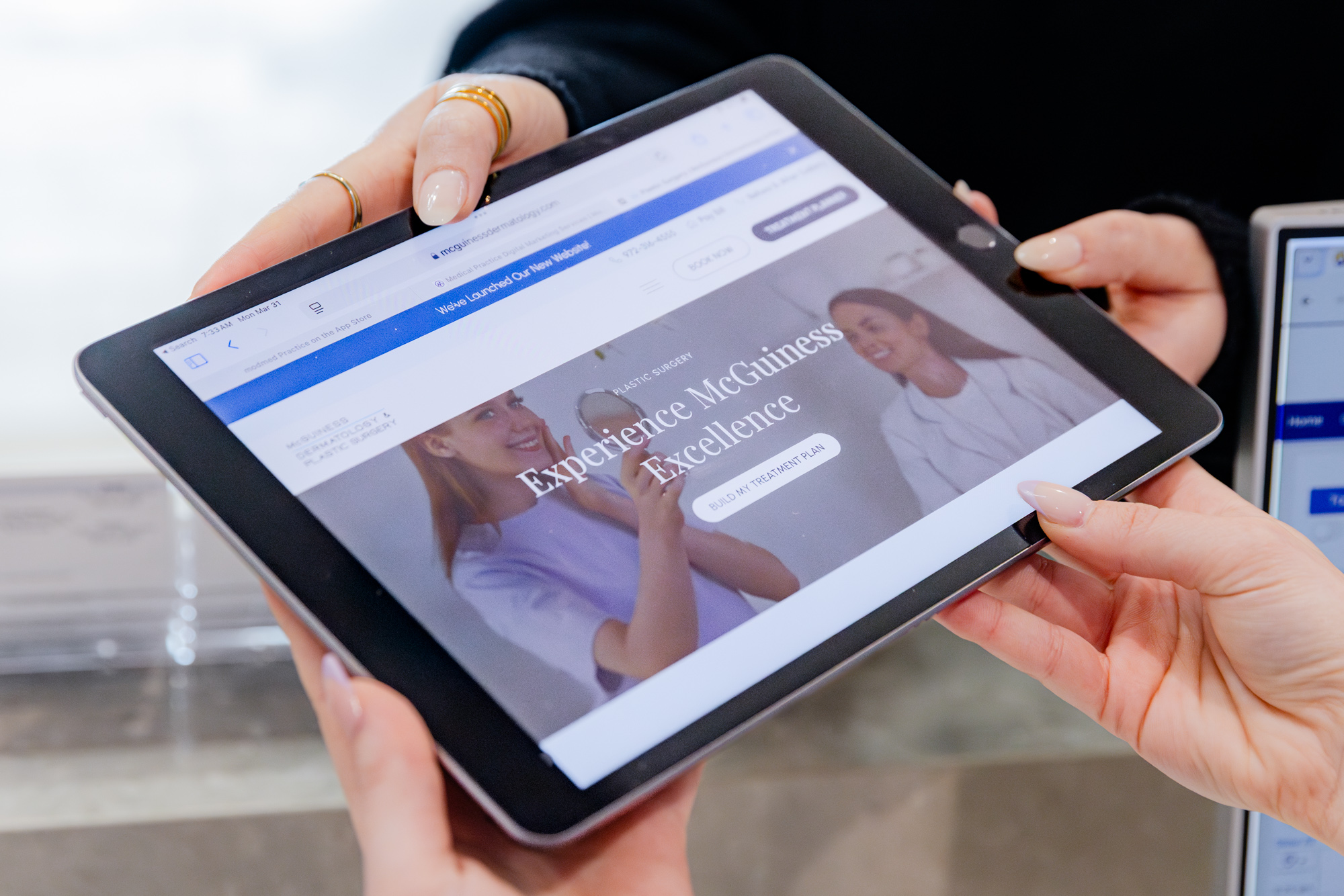 Hands hold a tablet with the McGuiness Dermatology and Plastic Surgery website home page displayed on it. This is the first step to booking an appointment for the Clear and Brilliant laser near Frisco.